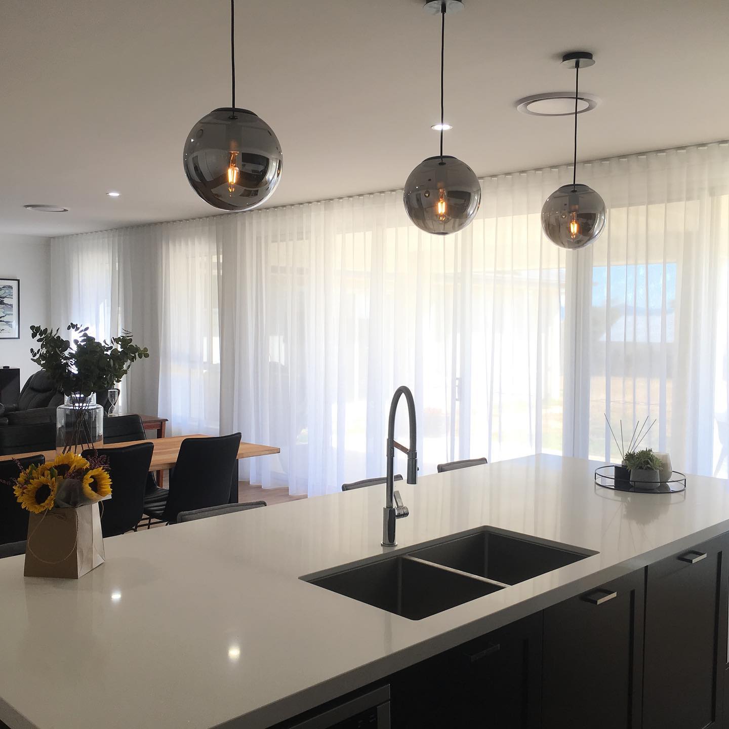Sheer curtains and pendant lighting above a kitchen island