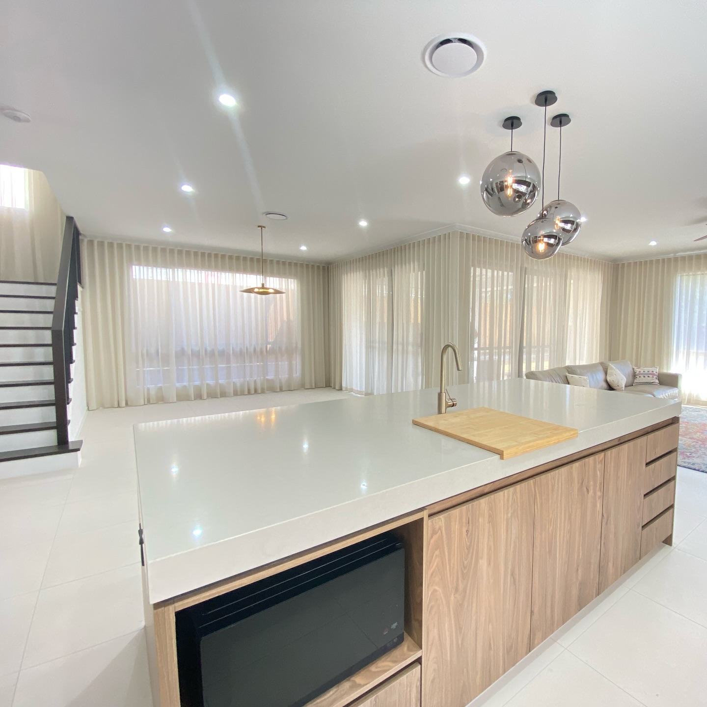 Sheer curtains in an open-plan kitchen and living area with staircase