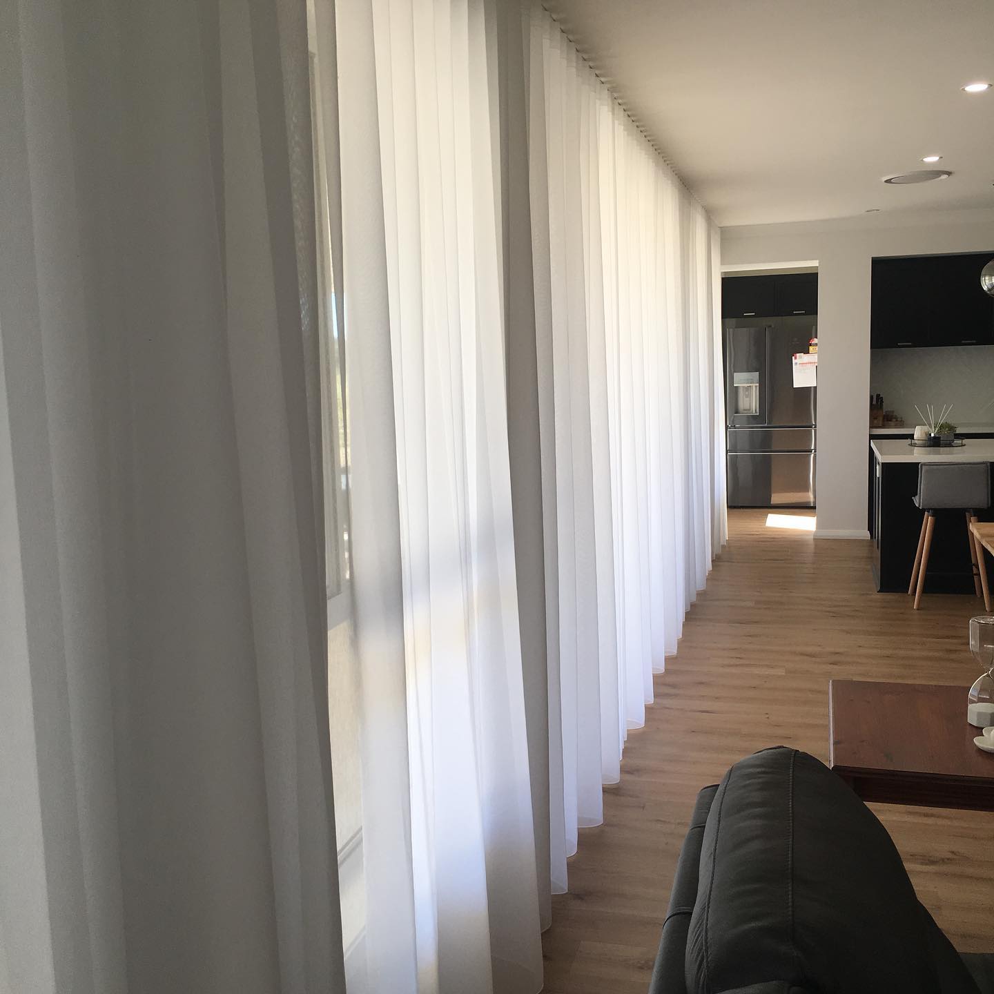 Floor-to-ceiling sheer curtains along a hallway into the kitchen