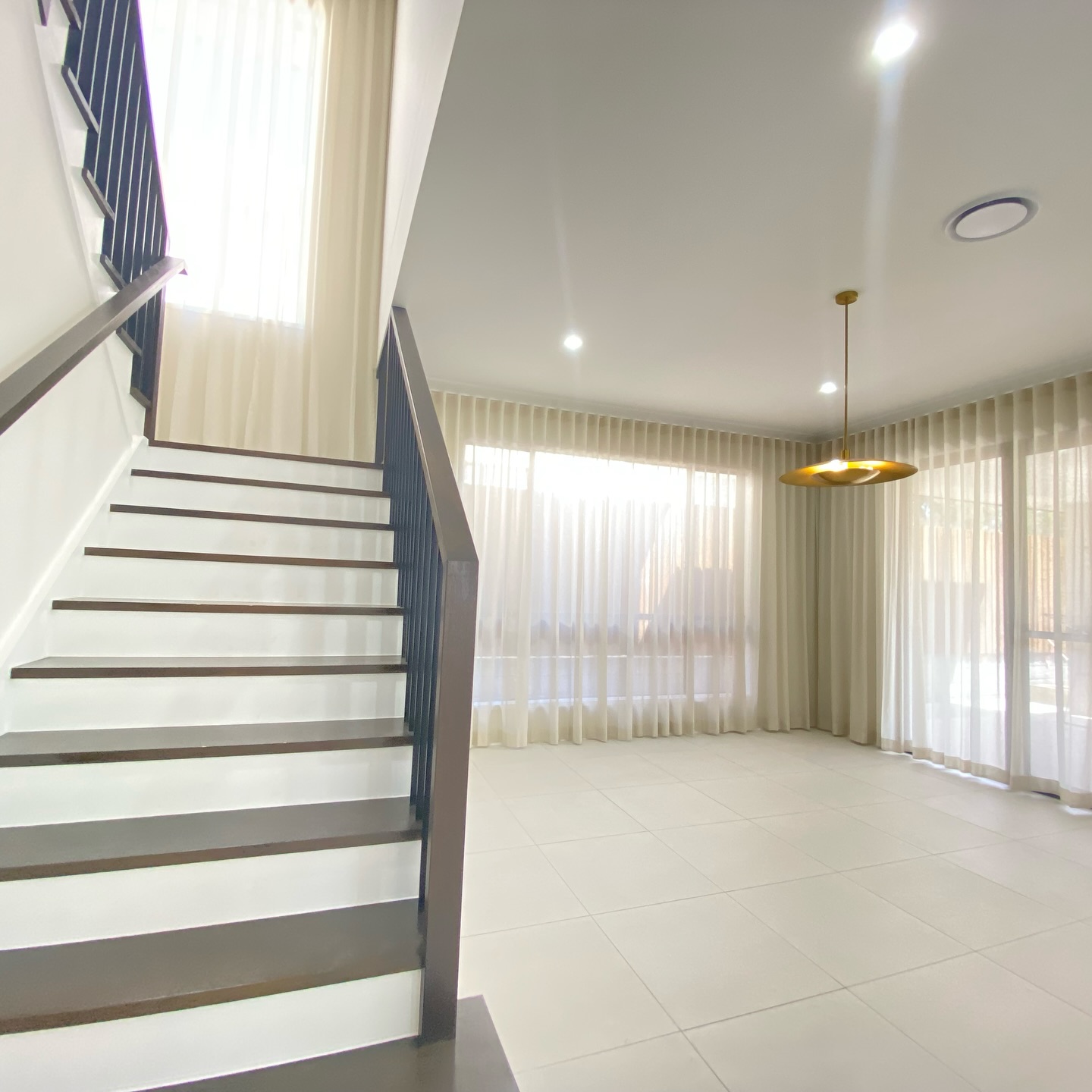Sheer curtains near a staircase and open living area